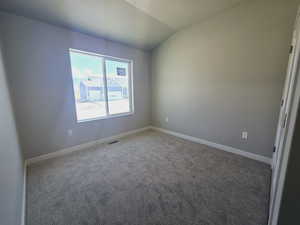 Carpeted spare room featuring lofted ceiling