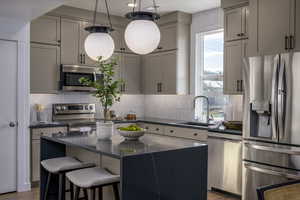 Kitchen with a wealth of natural light, a center island, sink, and appliances with stainless steel finishes. *Model Home Photo. Colors and finishes will vary.