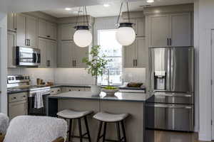 Kitchen with dark hardwood / wood-style floors, tasteful backsplash, stainless steel appliances, sink, and cabinets. *Model Home Photo. Colors and finishes will vary.