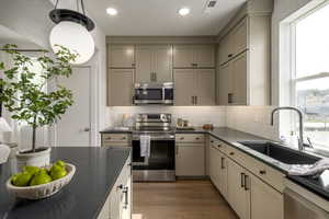 Kitchen with a wealth of natural light, dark wood-type flooring, stainless steel appliances, and tasteful backsplash. *Model Home Photo. Colors and finishes will vary.