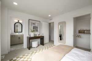 Carpeted bedroom featuring ensuite bath, sink, and a closet. *Model Home Photo. Colors and finishes will vary.