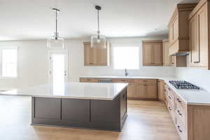 Kitchen featuring tile backsplash, gas cooktop, island, sink, and GE Cafe appliances with stainless steel finishes.