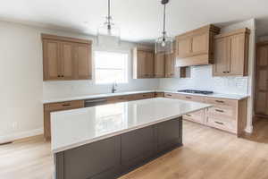 Kitchen featuring quartz countertops, custom wood range hood and window over the sink to a private backyard