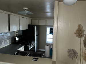 Kitchen with gas stove, decorative backsplash, and white cabinets