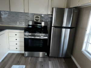 Kitchen with stainless steel appliances, tasteful backsplash, and dark hardwood / wood-style floors