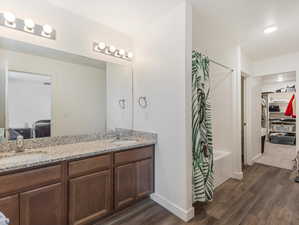 Bathroom with hardwood / wood-style flooring, shower / tub combo with curtain, and vanity