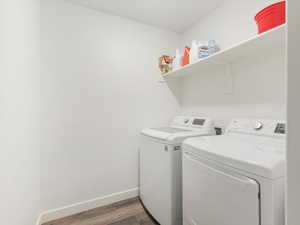 Clothes washing area with hardwood / wood-style flooring and washing machine and dryer