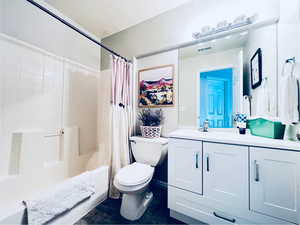 Full bathroom featuring vanity, toilet, and shower / bathtub combination with curtain