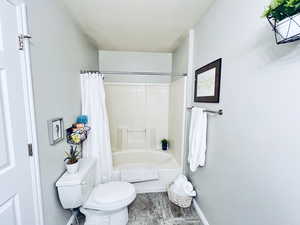 Bathroom with toilet and shower / bathtub combination with curtain