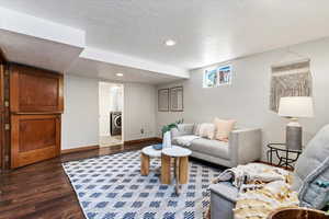 Living room with dark wood-type flooring, a textured ceiling, and washer / clothes dryer