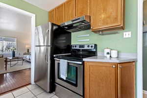 Kitchen featuring light hardwood / wood-style flooring, electric range, and exhaust hood