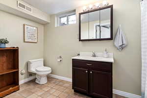 Bathroom with tile patterned flooring, toilet, a textured ceiling, and vanity