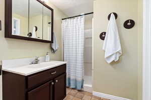 Bathroom featuring a textured ceiling, vanity, and curtained shower