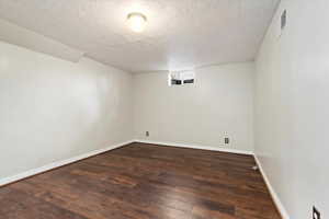 Empty room featuring dark hardwood / wood-style flooring and a textured ceiling