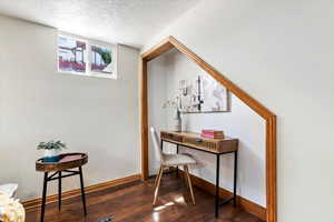 Office space with a textured ceiling and dark hardwood / wood-style flooring