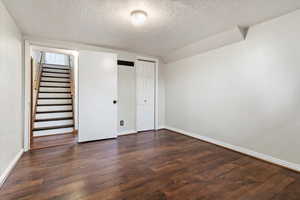 Unfurnished bedroom with a textured ceiling, dark hardwood / wood-style floors, and a closet