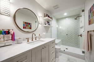 Bathroom featuring walk in shower, vanity, and toilet