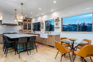 Kitchen with light stone counters, sink, pendant lighting, and a kitchen island