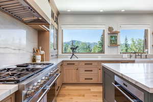 Kitchen with premium range hood, a wealth of natural light, sink, double oven range, and a mountain view