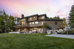 Back house at dusk featuring a yard and a patio area