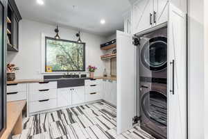 Washroom with stacked washer and clothes dryer and sink