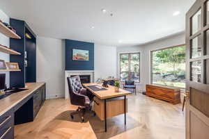 Home office with light parquet flooring and a fireplace