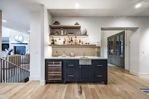 Bar featuring french doors, sink, beverage cooler, and light wood-type flooring
