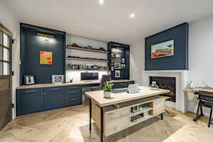 Office featuring a large fireplace, light parquet flooring, and built in desk