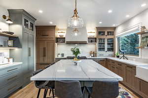 Kitchen featuring a spacious island, a breakfast bar, island range hood, paneled fridge, and light stone countertops