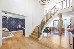 Stairway featuring hardwood / wood-style floors, a towering ceiling, and a chandelier