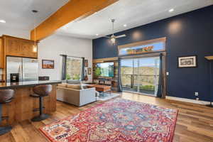 Living room featuring light wood-type flooring, a wealth of natural light, beam ceiling, and a high ceiling