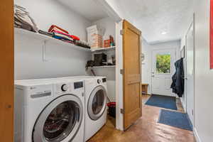 Laundry room with a textured ceiling and washing machine and clothes dryer