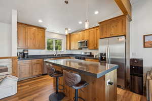 Kitchen featuring a center island, appliances with stainless steel finishes, lofted ceiling, pendant lighting, and a kitchen bar