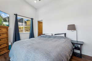 Bedroom featuring high vaulted ceiling and dark hardwood / wood-style flooring