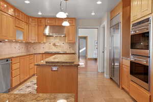 The use of natural wood gives the kitchen a rich, organic feel. The layout emphasizes an open, spacious design that facilitates ease of movement and interactions with Wolf and Subzero stainless steal appliances and elegant granite counter tops