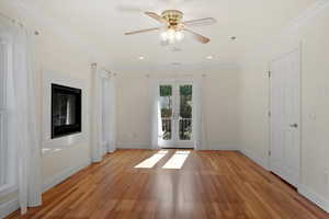 Well lit bedroom with fireplace, with can lights and ceiling fan.