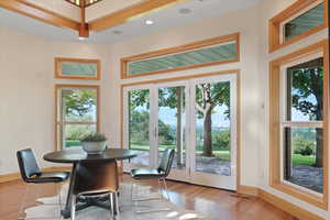 The dining area is positioned near large windows and glass doors that offer expansive views of the outdoors. These windows overlook a picturesque landscape