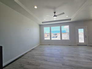 Empty room featuring ceiling fan, a raised ceiling, hardwood / wood-style flooring, and a textured ceiling