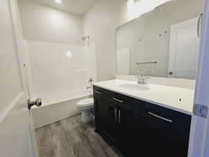 Full bathroom with shower / tub combination, wood-type flooring, vanity, and toilet