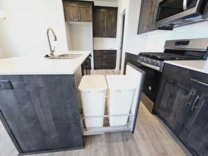 Kitchen with sink, tasteful backsplash, a center island with sink, light hardwood / wood-style flooring, and appliances with stainless steel finishes