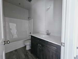 Full bathroom with vanity, toilet, hardwood / wood-style flooring, and shower / bathing tub combination