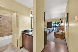 Bathroom featuring tiled shower / bath combo, hardwood / wood-style flooring, and vanity