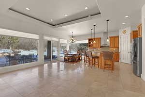 Dining room featuring light tile patterned floors, a tray ceiling, and a notable chandelier