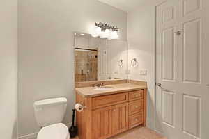 Bathroom featuring toilet, tile patterned flooring, walk in shower, and vanity