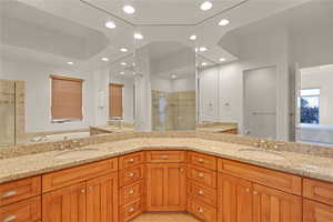 Bathroom with double vanity, a shower stall, a sink, and recessed lighting