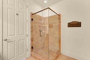 Bathroom with baseboards, recessed lighting, a shower stall, and tile patterned floors