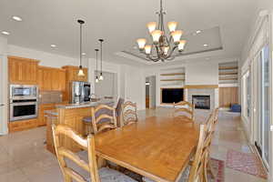 Dining area featuring light tile patterned floors, a fireplace, a raised ceiling, and recessed lighting