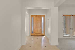 Foyer entrance featuring light tile patterned floors, french doors, light carpet, and baseboards