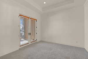 Carpeted empty room featuring visible vents, a tray ceiling, baseboards, and recessed lighting