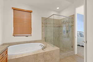 Ensuite bathroom featuring a stall shower, tile patterned flooring, a garden tub, and vanity